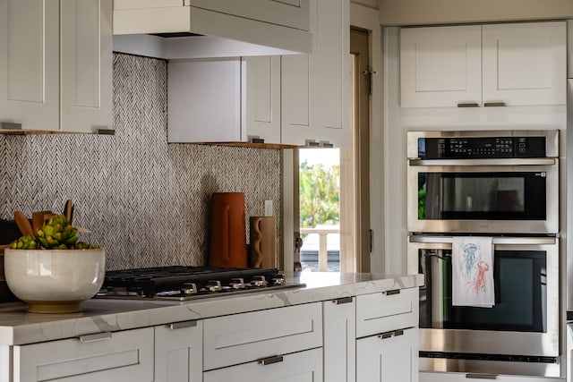 kitchen featuring white cabinets, light stone countertops, decorative backsplash, and stainless steel appliances