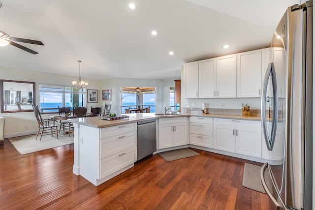 kitchen featuring appliances with stainless steel finishes, dark hardwood / wood-style flooring, kitchen peninsula, and decorative light fixtures