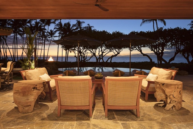 patio terrace at dusk featuring an outdoor hangout area, a water view, and ceiling fan