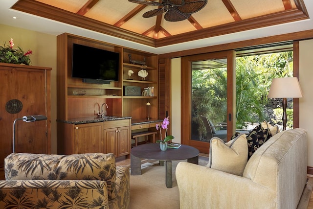 carpeted living room featuring a raised ceiling, ceiling fan, and ornamental molding