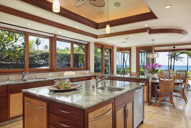 kitchen featuring pendant lighting, a water view, sink, and a kitchen island with sink