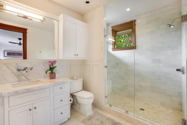 bathroom with tile patterned floors, toilet, vanity, a shower with door, and backsplash