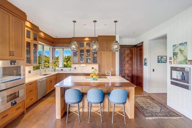 kitchen with sink, light hardwood / wood-style flooring, a center island, decorative light fixtures, and stainless steel dishwasher