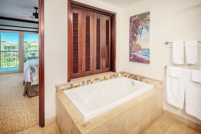 bathroom featuring ceiling fan, a relaxing tiled bath, and tile flooring