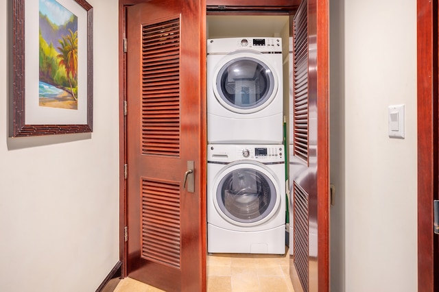 laundry area with stacked washer / drying machine and light tile floors