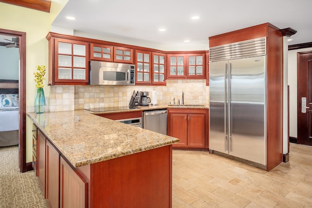 kitchen with light stone counters, appliances with stainless steel finishes, light tile floors, sink, and tasteful backsplash