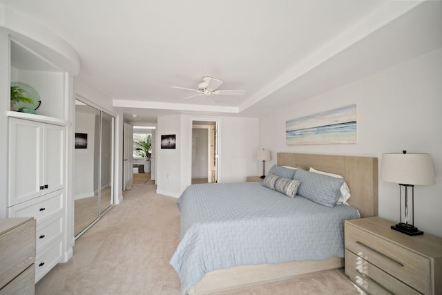 carpeted bedroom with ceiling fan and a raised ceiling