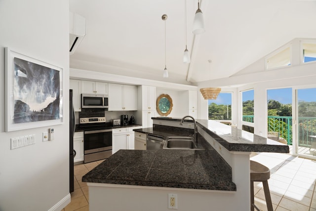 kitchen featuring pendant lighting, white cabinets, stainless steel appliances, light tile floors, and a center island with sink