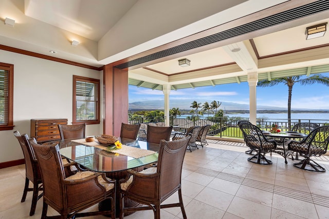 dining room featuring a water view and light tile floors