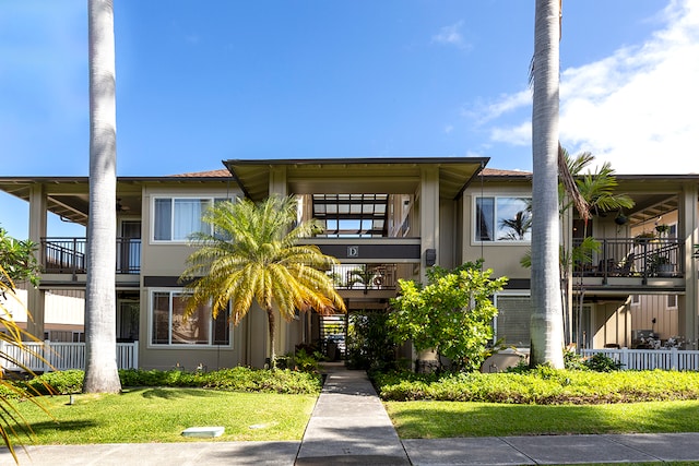 view of front of property featuring a balcony and a front yard