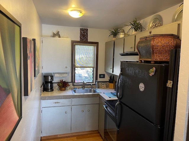 kitchen featuring light hardwood / wood-style flooring, sink, tasteful backsplash, and black appliances