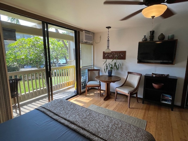 sitting room with wood-type flooring, a wall mounted air conditioner, a wealth of natural light, and ceiling fan