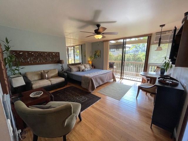 bedroom featuring hardwood / wood-style floors, a wall unit AC, ceiling fan, and access to outside