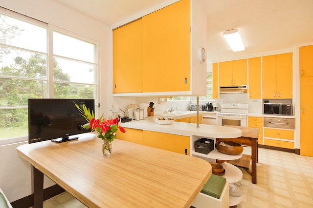 kitchen with stainless steel microwave, electric range, kitchen peninsula, and plenty of natural light