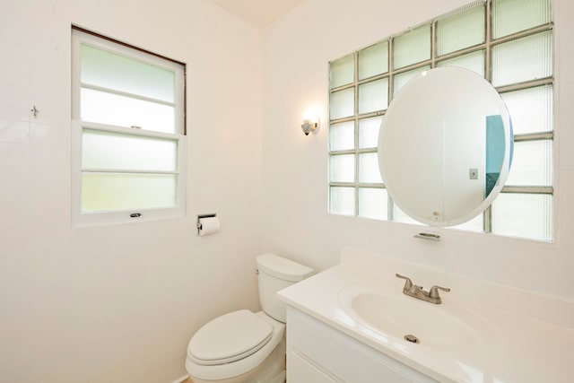 bathroom featuring a healthy amount of sunlight, oversized vanity, and toilet