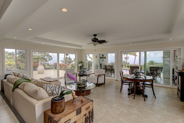 sunroom featuring ceiling fan, a raised ceiling, and a wealth of natural light