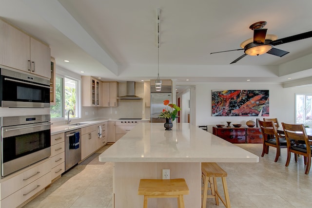 kitchen featuring a center island, plenty of natural light, wall chimney range hood, and backsplash