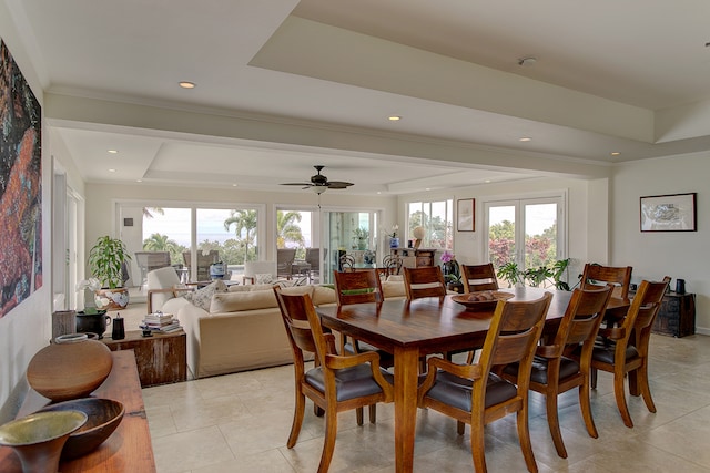 dining area featuring light tile floors, a healthy amount of sunlight, ceiling fan, and a raised ceiling