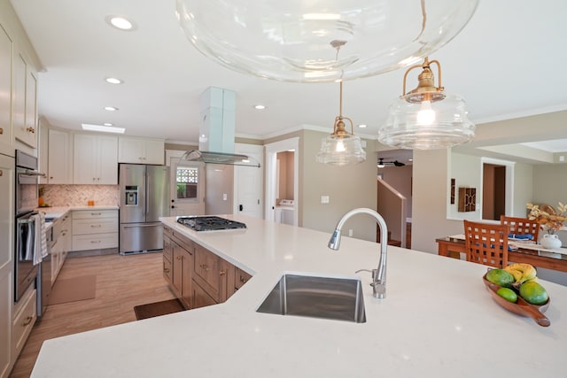 kitchen featuring hanging light fixtures, sink, island exhaust hood, light hardwood / wood-style flooring, and stainless steel appliances