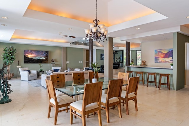 dining area with a notable chandelier, a raised ceiling, and light tile floors