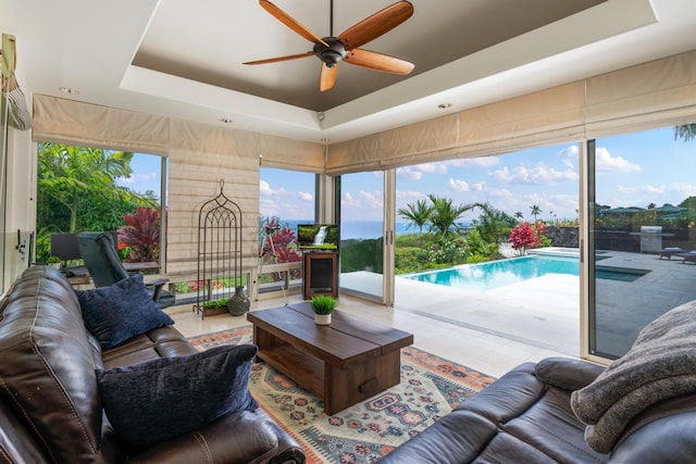 tiled living room featuring ceiling fan and a raised ceiling