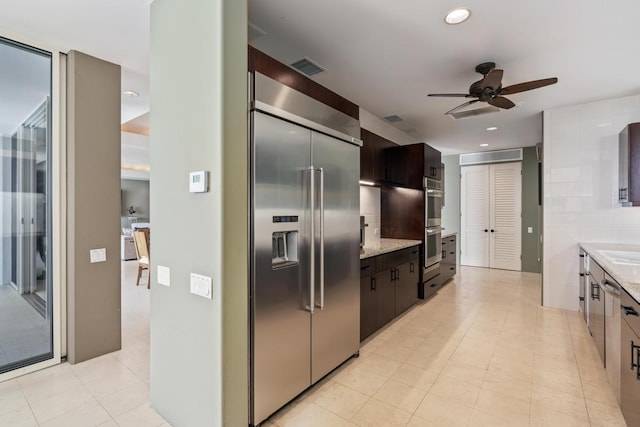 kitchen with dark brown cabinetry, ceiling fan, light tile floors, and stainless steel appliances