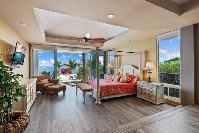 bedroom with multiple windows, ceiling fan, access to exterior, and hardwood / wood-style flooring