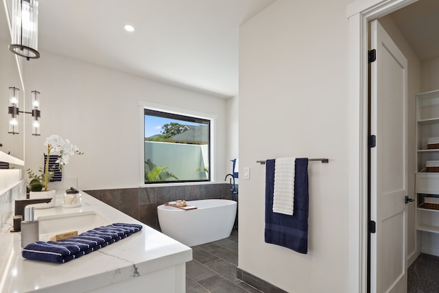 bathroom featuring tile flooring, a washtub, vanity, and tile walls