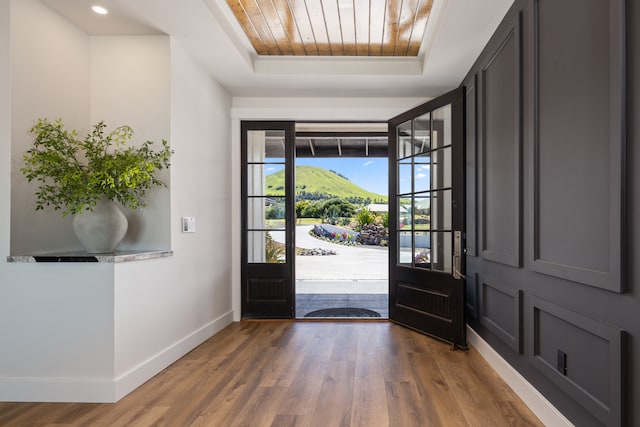 entryway with hardwood / wood-style flooring, wood ceiling, and a raised ceiling