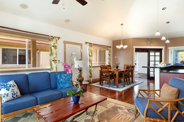 living room featuring lofted ceiling, ceiling fan with notable chandelier, and dark hardwood / wood-style flooring