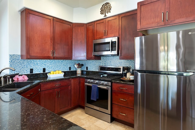 kitchen with sink, tasteful backsplash, stainless steel appliances, and dark stone countertops