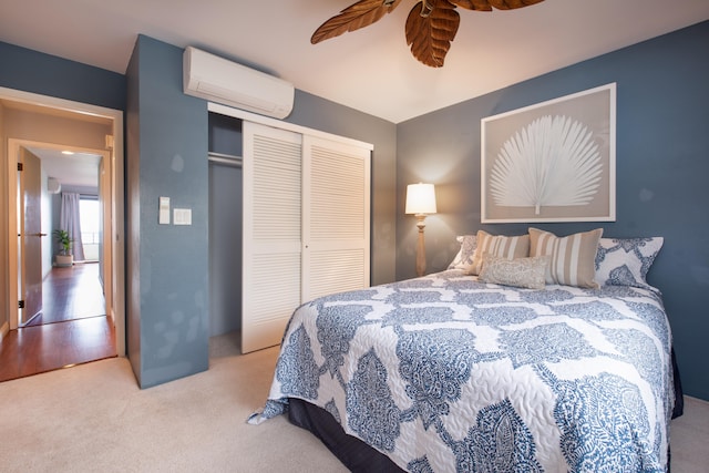 bedroom featuring ceiling fan, light colored carpet, a closet, and a wall mounted AC