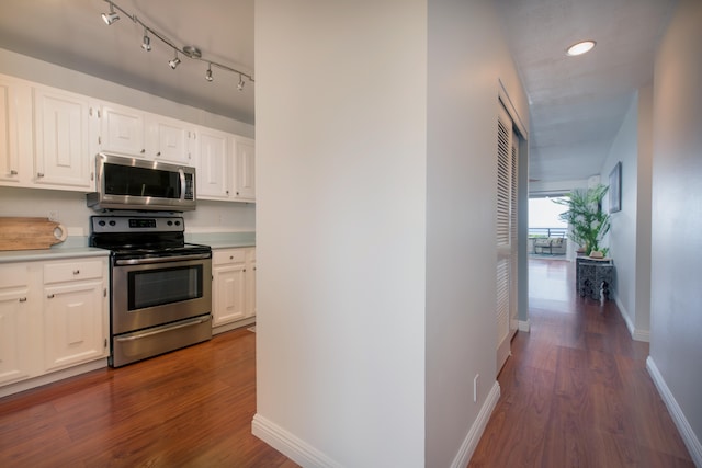 kitchen with stainless steel appliances, dark hardwood / wood-style floors, track lighting, and white cabinets