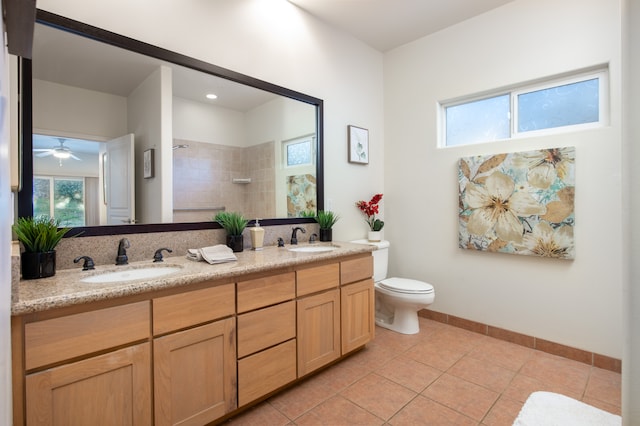 bathroom featuring dual bowl vanity, toilet, ceiling fan, tile floors, and a tile shower