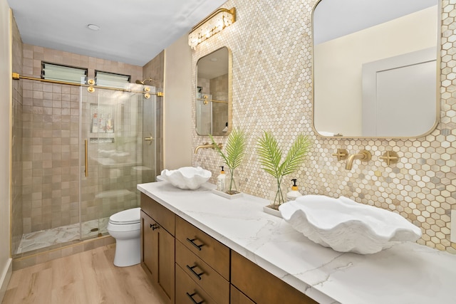 bathroom featuring an enclosed shower, hardwood / wood-style flooring, dual bowl vanity, tile walls, and toilet