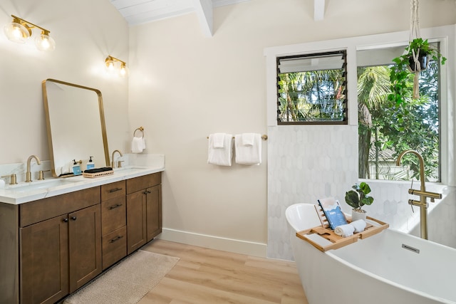 bathroom with beamed ceiling, a bathtub, wood-type flooring, and double sink vanity