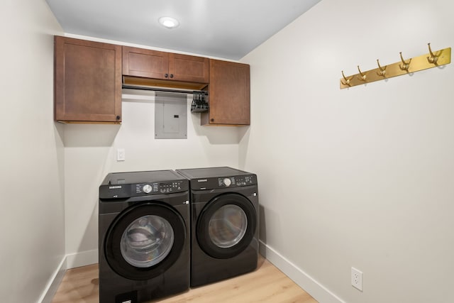 laundry area featuring cabinets, washer and clothes dryer, and light hardwood / wood-style flooring