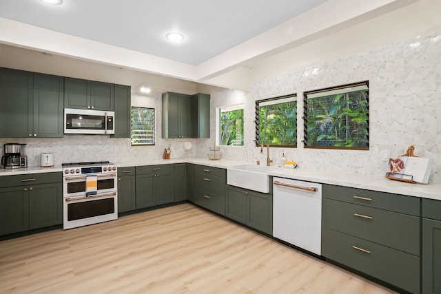 kitchen with white appliances, green cabinetry, and light wood-type flooring