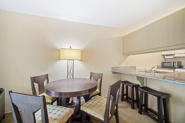 dining room with light carpet and sink