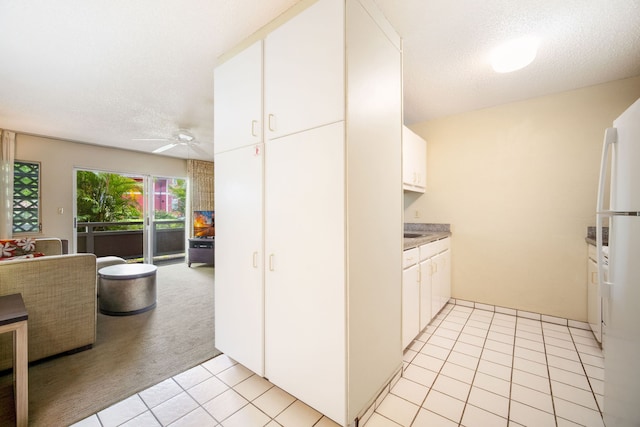 kitchen with white cabinets, a textured ceiling, light carpet, white fridge, and ceiling fan