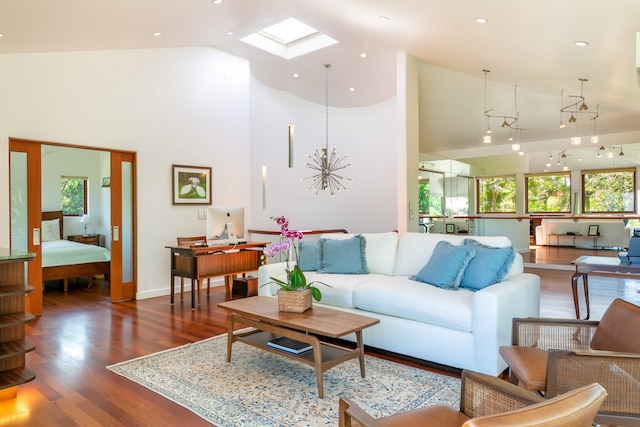 living room featuring high vaulted ceiling, hardwood / wood-style flooring, and a skylight