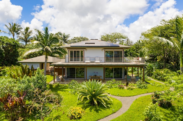 rear view of house with a patio area, a lawn, and a balcony