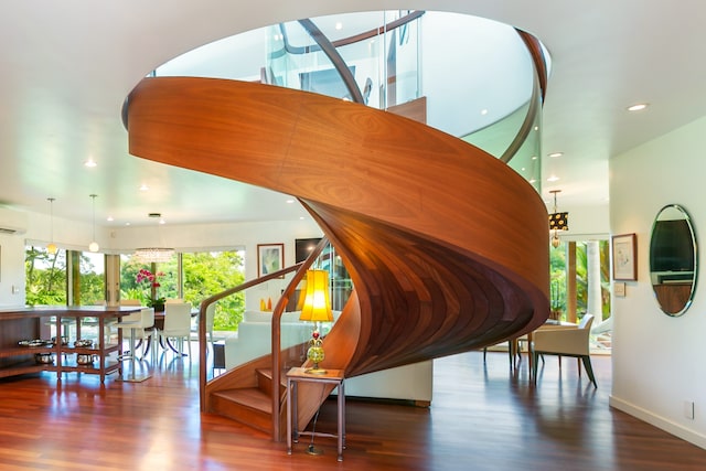 stairs featuring an AC wall unit, a notable chandelier, plenty of natural light, and dark hardwood / wood-style flooring