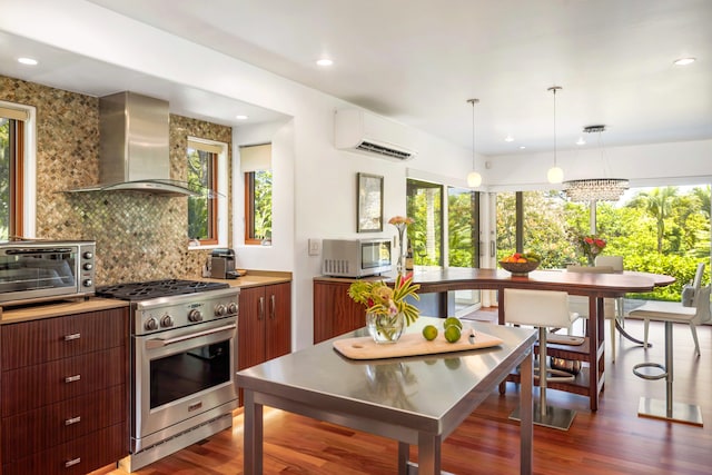 kitchen featuring appliances with stainless steel finishes, wall chimney range hood, plenty of natural light, and dark hardwood / wood-style flooring