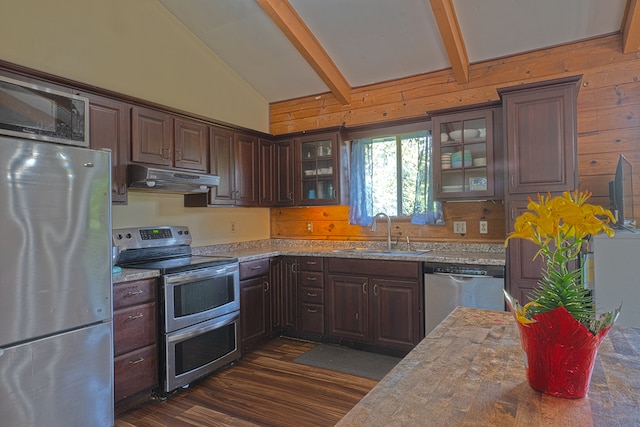 kitchen featuring wood walls, stainless steel appliances, lofted ceiling with beams, sink, and dark hardwood / wood-style flooring