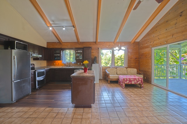 kitchen featuring wooden walls, high vaulted ceiling, tile floors, appliances with stainless steel finishes, and beam ceiling