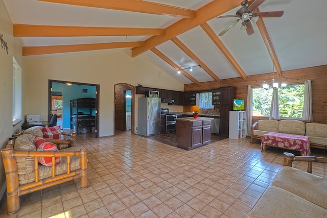 living room with beamed ceiling, ceiling fan, high vaulted ceiling, light tile flooring, and wooden walls