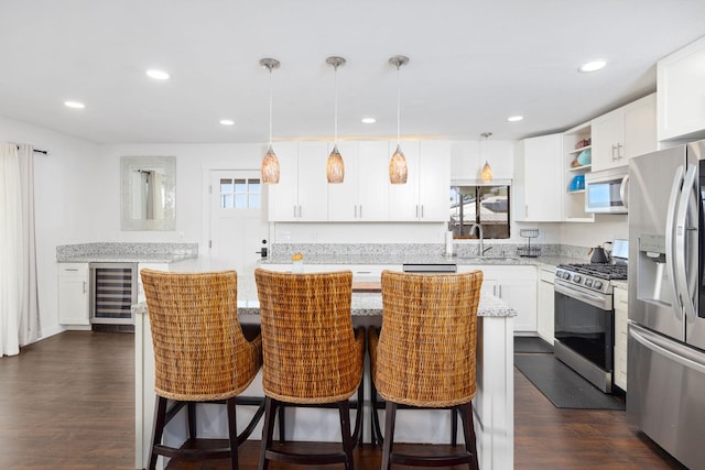 kitchen with a kitchen island, dark wood-type flooring, stainless steel appliances, white cabinetry, and a sink