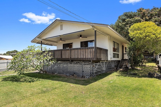 view of front of house with stucco siding, a ceiling fan, and a front yard