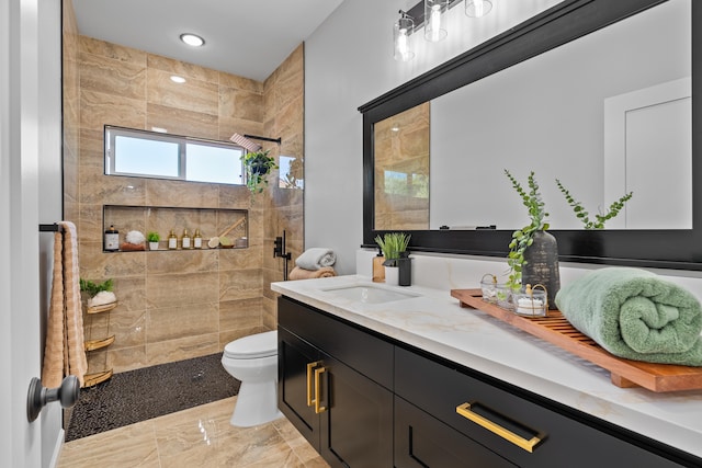 bathroom with toilet, vanity, and tiled shower